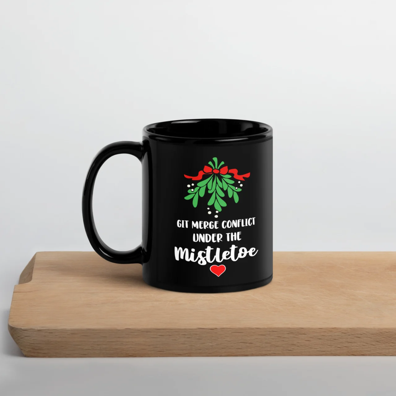 Black ceramic Git Merge Conflict Under Mistletoe Mug featuring a graphic of mistletoe and the white text: "GIT MERGE CONFLICT UNDER THE MISTLETOE." This is a funny Git Programmer Christmas Mug