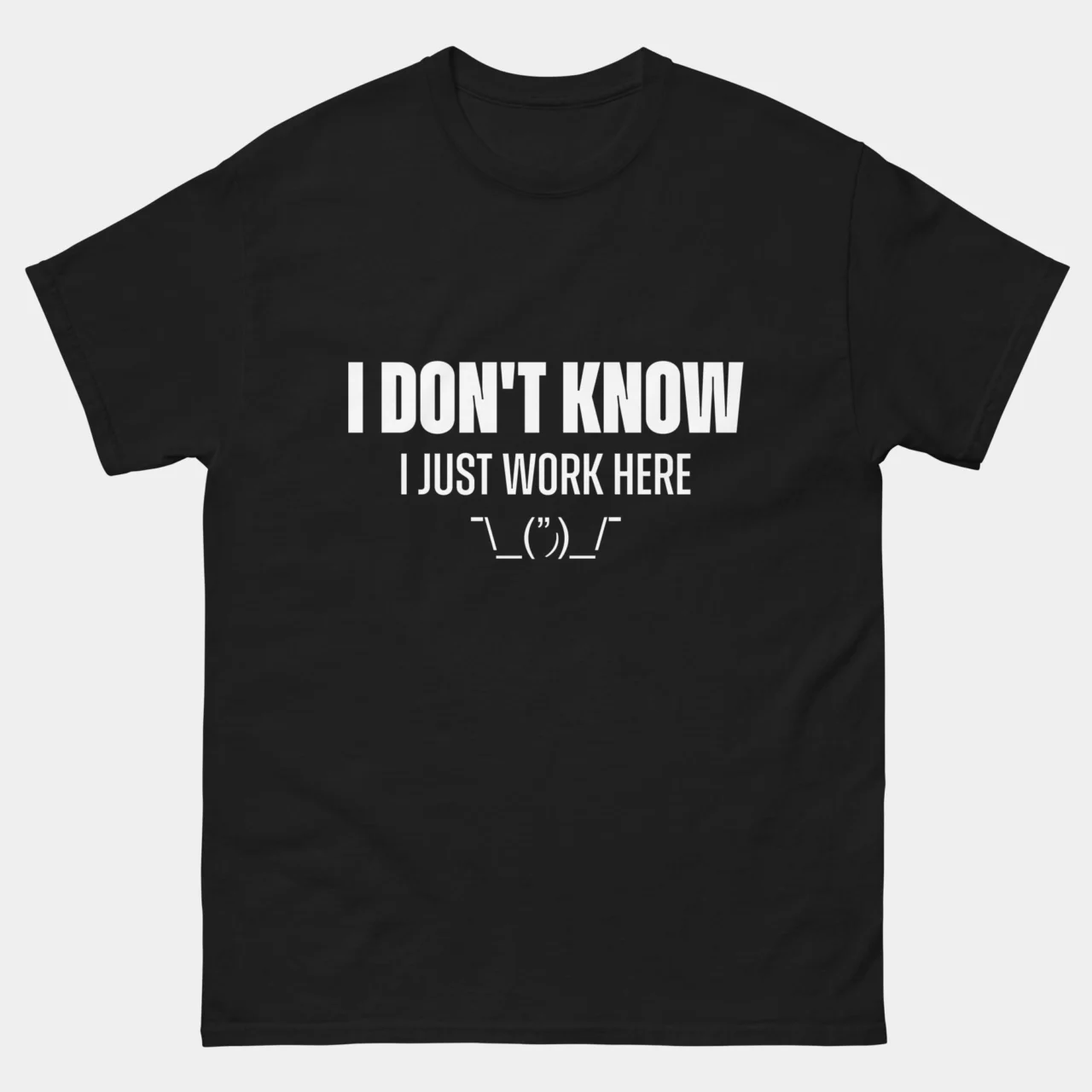 Black sarcastic Funny Office Shirt with bold white text reading I Don't Know I Just Work Here followed by a shruggie ASCII emoticon, funny IT support and helpdesk graphic tee for relatable employees
