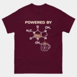 Maroon Powered By Caffeine Funny Chemistry Shirt showing the caffeine molecule structure pouring into a coffee mug above the text Powered By, science humor graphic tee for chemists and coffee lovers